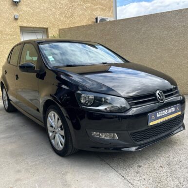 Volkswagen Polo noire brillante, 5 portes, plaque Access Auto Pamiers, stationnée devant un mur crème.