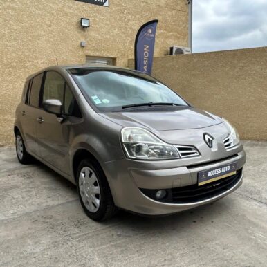 Renault Modus grise d'occasion devant le garage Access Auto sur un parking bétonné par temps nuageux.